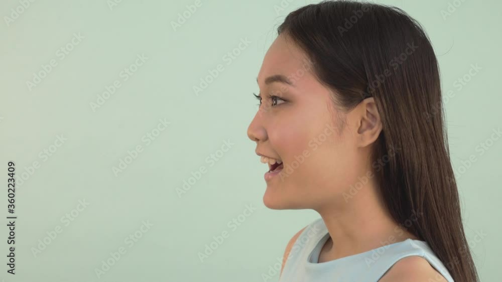 Close-up profile portrait. WHAT? Shocked surprised joyful asian girl looking at the camera. video blue isolated background. 4K Close-up profile portrait. WHAT? Shocked surprised joyful asian girl looking at the camera. video blue isolated background. 4K
