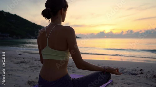 Yoga meditation, woman meditating at beach sunset or sunrise relaxing in yoga pose. Serene relaxed female yoga in calm nature sea scene.