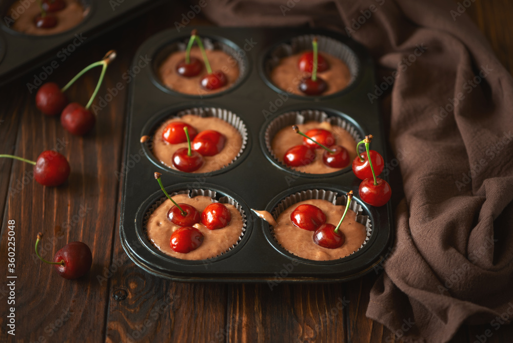 Baking chocolate muffins. Raw vegan banana cherry muffins with fresh berries on brown wooden background. Top view. Summer food Baking chocolate muffins. Raw vegan banana cherry muffins with fresh berries on brown wooden background. Top view. Summer food