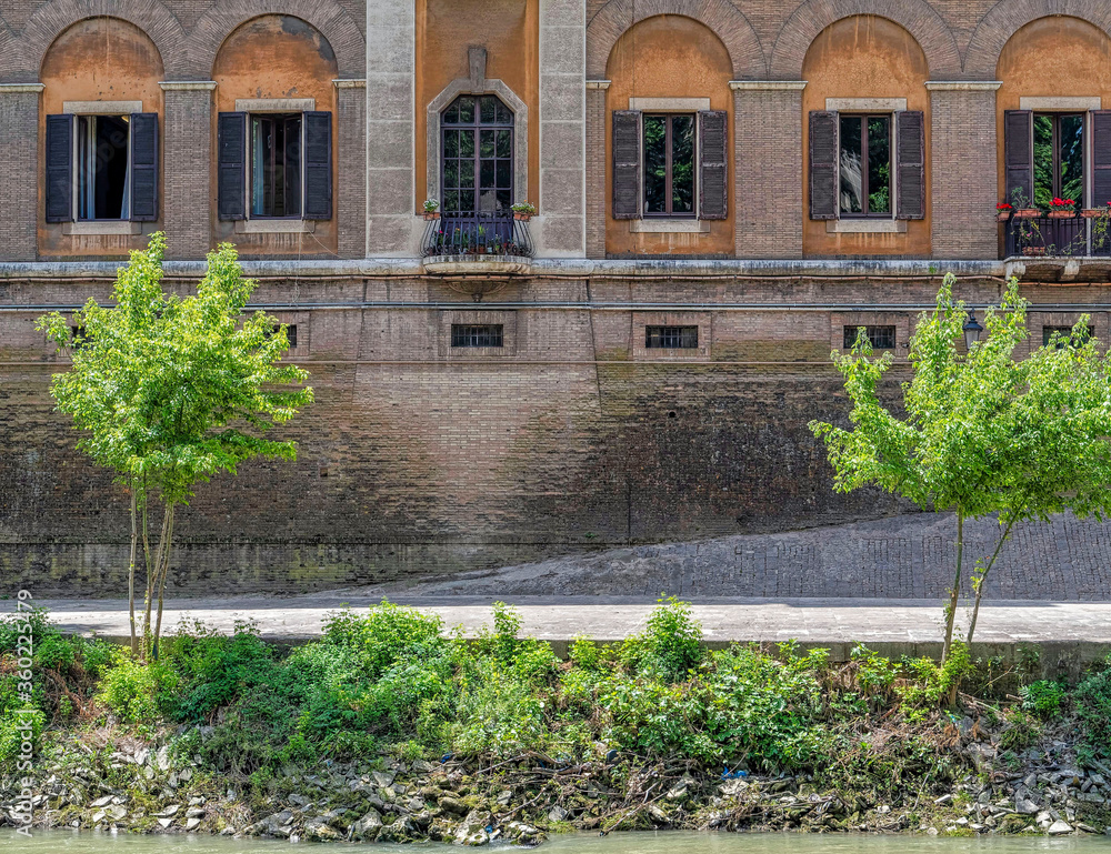 vintage apartment building decorated facade with windows pattern on Tiber river, Rome Italy