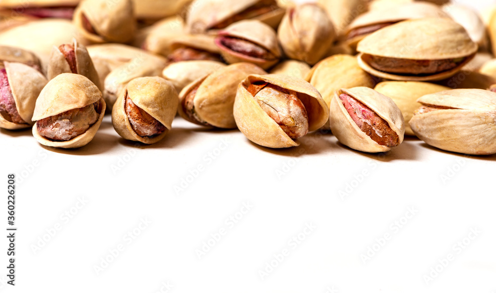 Pile of salted pistachios on a white background closeup selective focus. Pistachios background, free space for text. Pile of salted pistachios on a white background closeup selective focus. Pistachios background, free space for text.