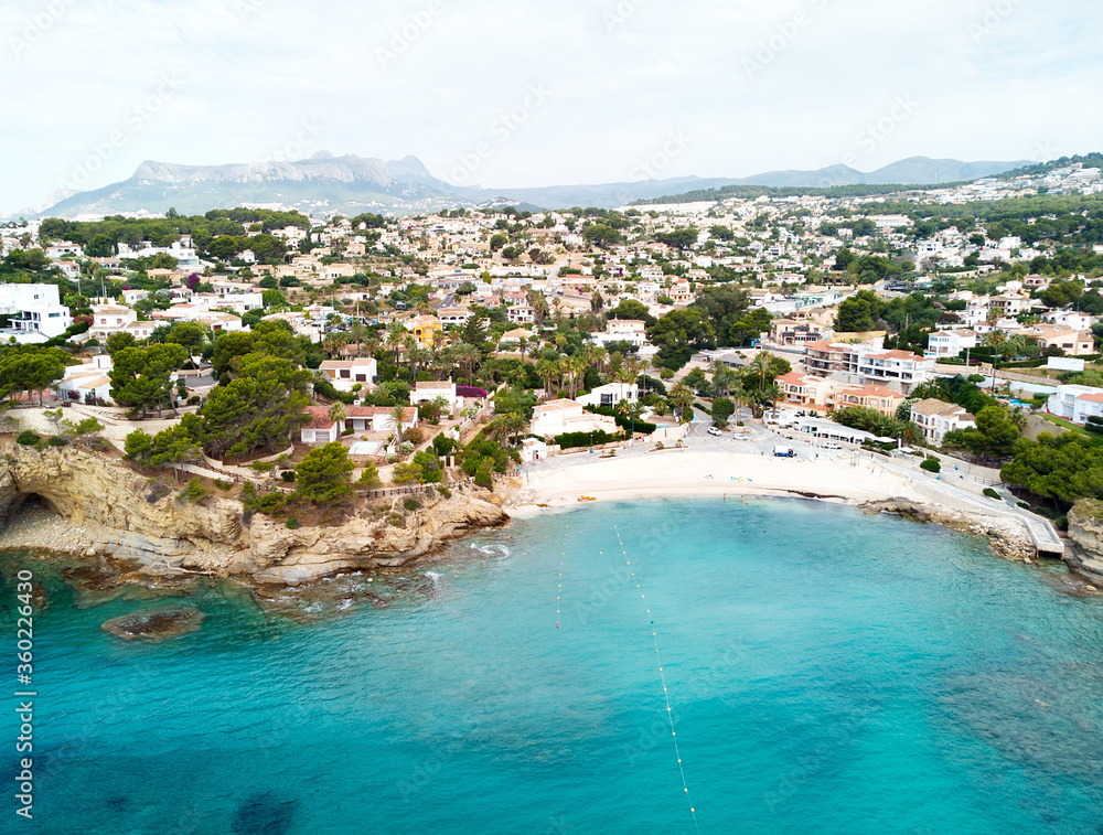 Distant view rocky coves, sandy beach, tiny bay of Benissa. Turquoise bright blue Sea waters hillside townscape at sunny day. Aerial photo drone point of view photography. Costa Blanca. Espana. Spain