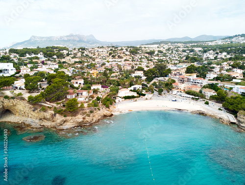 Distant view rocky coves, sandy beach, tiny bay of Benissa. Turquoise bright blue Sea waters hillside townscape at sunny day. Aerial photo drone point of view photography. Costa Blanca. Espana. Spain