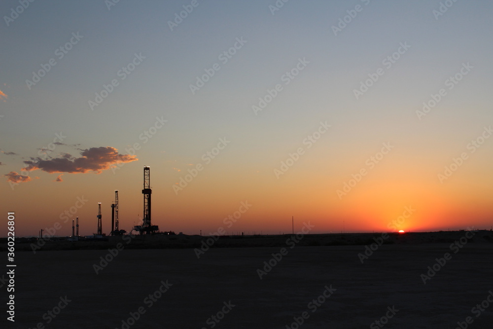 sunset over scenic West Texas landscape with FIVE drilling rigs in the background
