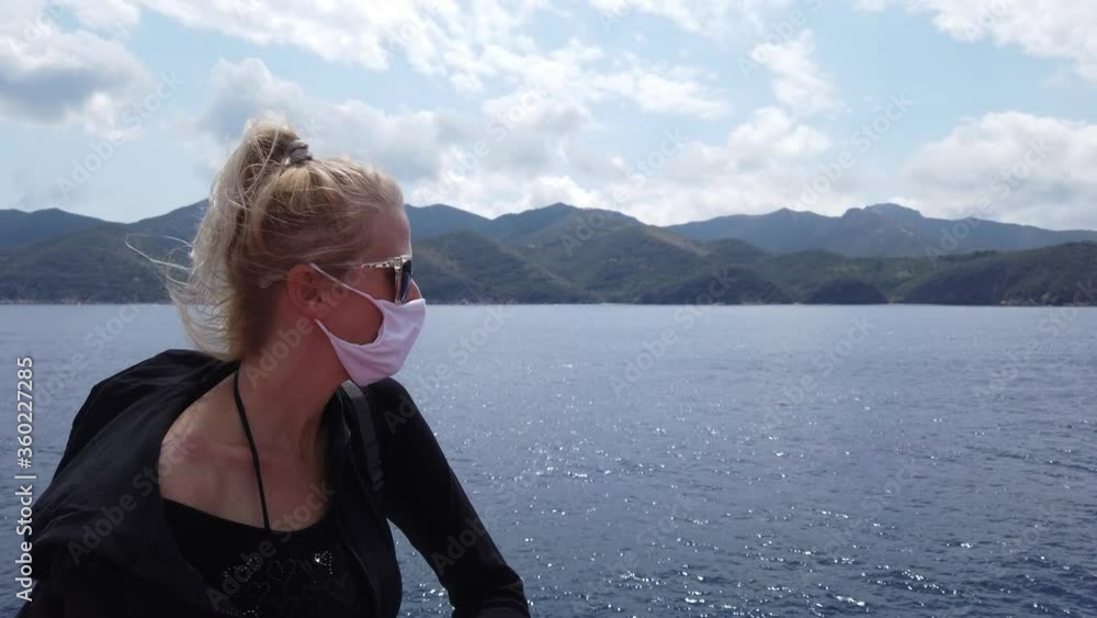 Woman on ferry boat with a surgical mask during Covid-19. Italian tourist woman travels on Tyrrhenian Sea to Elba Island by ferry boat. Coronavirus quarantine holiday travel in COVID pandemic in Italy Woman on ferry boat with a surgical mask during Covid-19. Italian tourist woman travels on Tyrrhenian Sea to Elba Island by ferry boat. Coronavirus quarantine holiday travel in COVID pandemic in Italy