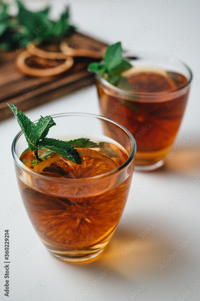 Golden drink, iced tea with a ring of dried orange and mint on a white background. Golden drink, iced tea with a ring of dried orange and mint on a white background.