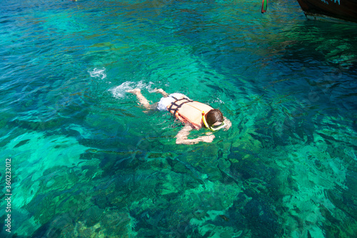 Young lady snorkeling in a tropical sea near sandy beach