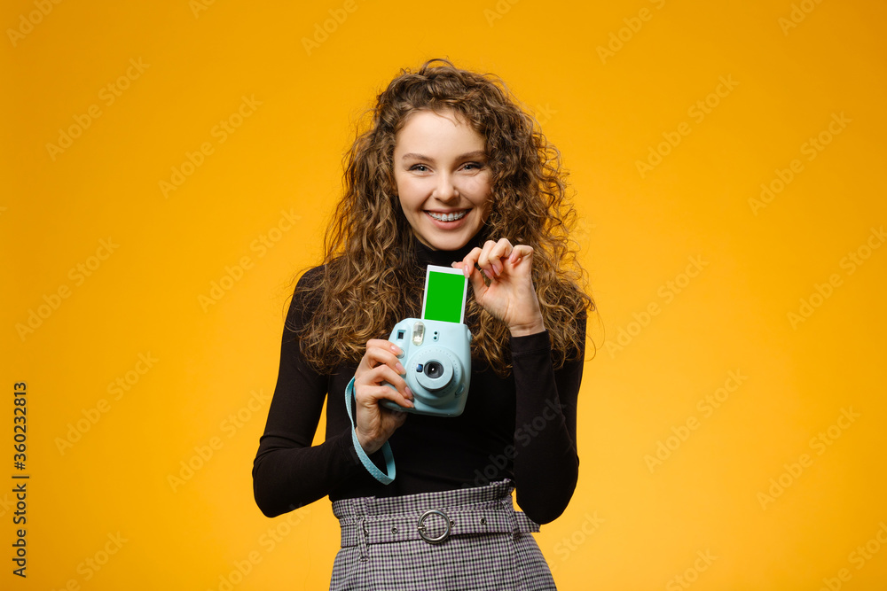 Beautiful girl with photo camera isolated on yellow background Beautiful girl with photo camera isolated on yellow background