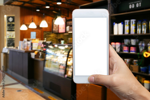 Close up hand hold and touch screen smartphone or cellphone with blank black screen for put it on your own webpage or message over blurred coffee shop background