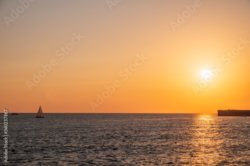 Beautiful yellow and orange sunset over the sea. The sun goes down over the sea. Silhouette of sea port at sunset