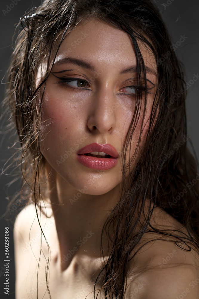 The face of a beautiful young girl with wet black hair close-up. Eastern appearance. Nude makeup, natural skin. The face of a beautiful young girl with wet black hair close-up. Eastern appearance. Nude makeup, natural skin.
