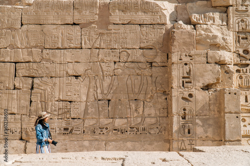 A woman with a camera walking In the ancient ruins of Egypt.