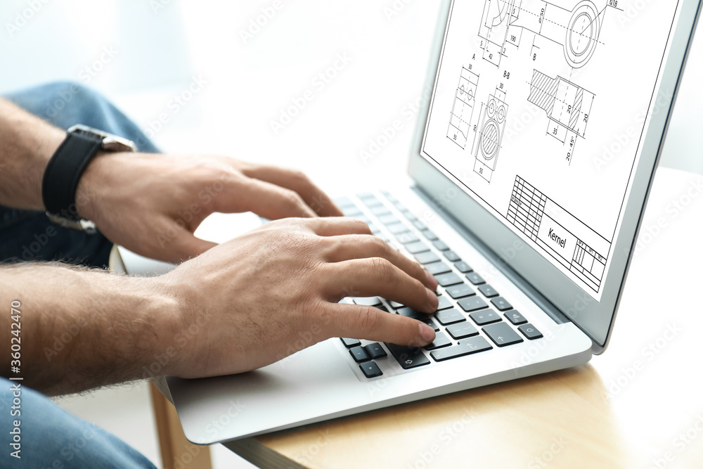 Male engineer working with technical drawing on laptop at table, closeup Male engineer working with technical drawing on laptop at table, closeup