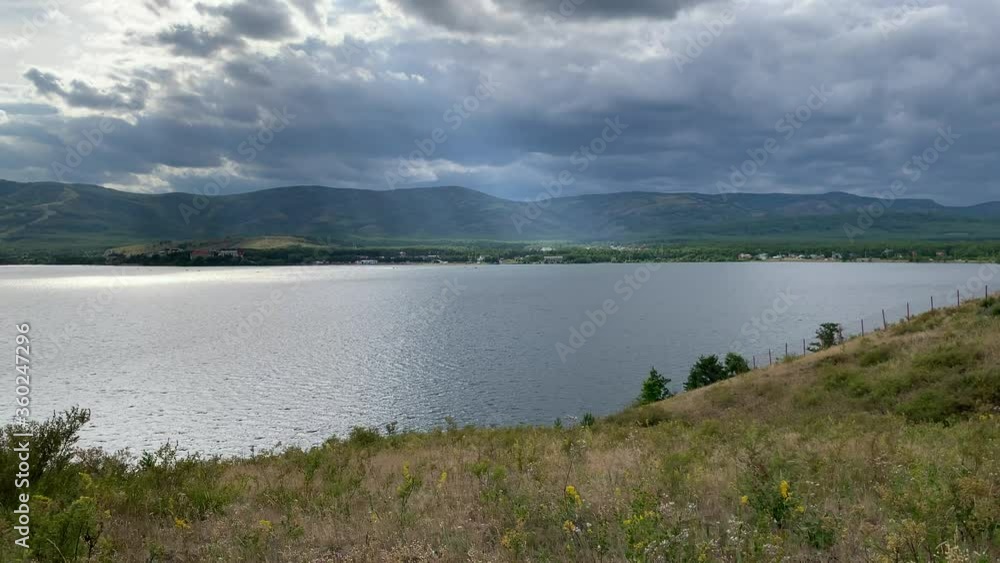 Summer landscape. Mountain lake. Beautiful blurred background of colourful flower. A large green field with trees and mountains in the background. A body of water with a mountain in the background Summer landscape. Mountain lake. Beautiful blurred background of colourful flower. A large green field with trees and mountains in the background. A body of water with a mountain in the background