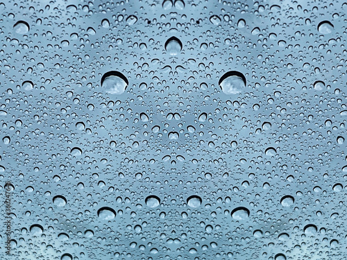 Raindrops on a glass pane with dark rain clouds in the background