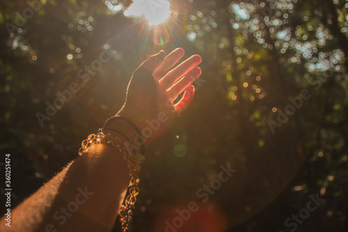 Hands reaching out to the light coming from the forest to show concept of mental health, hope and healing in nature  photo