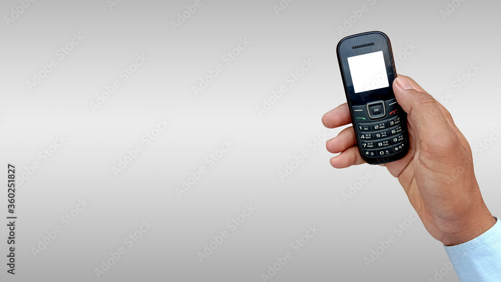 Asian man holding feature or keypad phone in hand Asian man holding feature or keypad phone in hand
