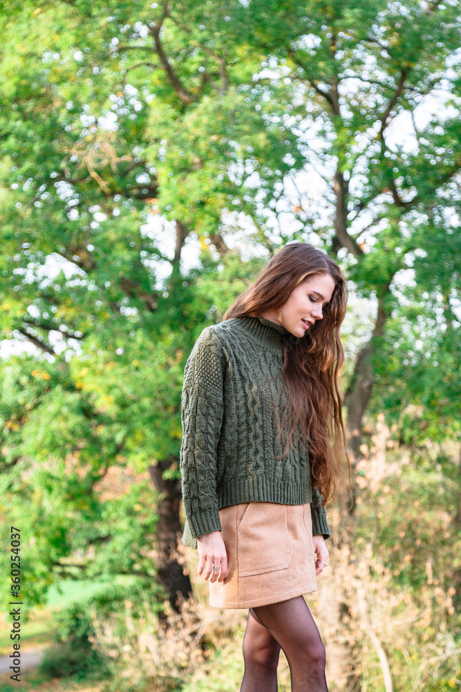 Girl in warm sweater on background of autumn trees Girl in warm sweater on background of autumn trees