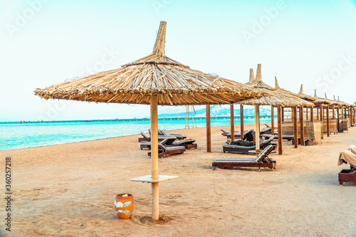 Fototapeta Naklejka Na Ścianę i Meble -  A beautiful beach with rustic bamboo umbrellas and a crystal clear sea