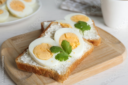 Tasty sandwiches with boiled eggs on wooden board, closeup
