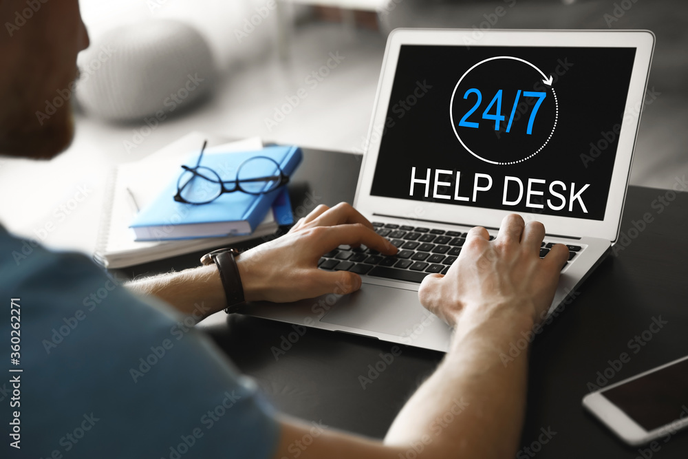 Man using laptop at table indoors, closeup. Help desk service Man using laptop at table indoors, closeup. Help desk service