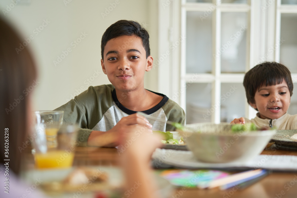 Portrait happy boy eating lunch with family at table Portrait happy boy eating lunch with family at table