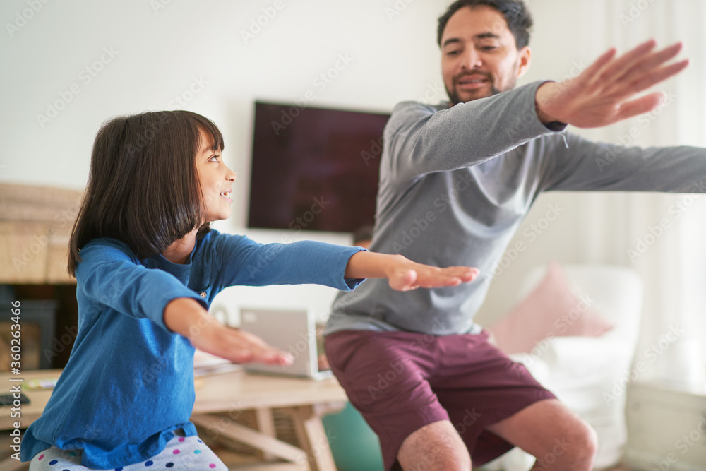 Father and daughter exercising doing squats in living room Father and daughter exercising doing squats in living room
