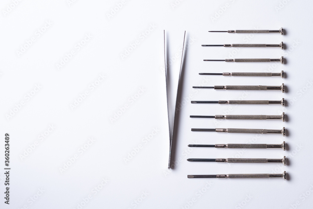 small parts and tweezers lie on a plain white background small parts and tweezers lie on a plain white background