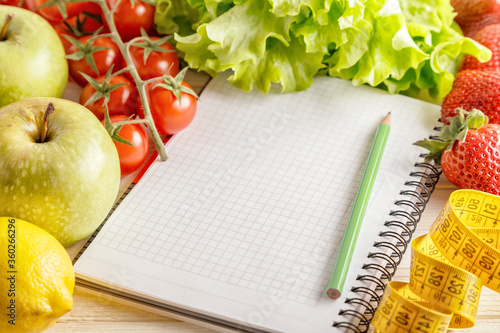 Fresh organic vegetables and fruits, open blank notebook and pen on wooden background.