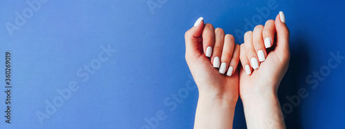 Banner with female hands and a white manicure on a blue background.