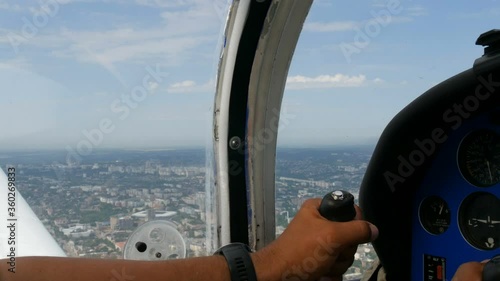 The hands of a professional pilot hold the helm and control panel of an airplane and pilot a small plane that flies over a megalopolis or big city background. photo