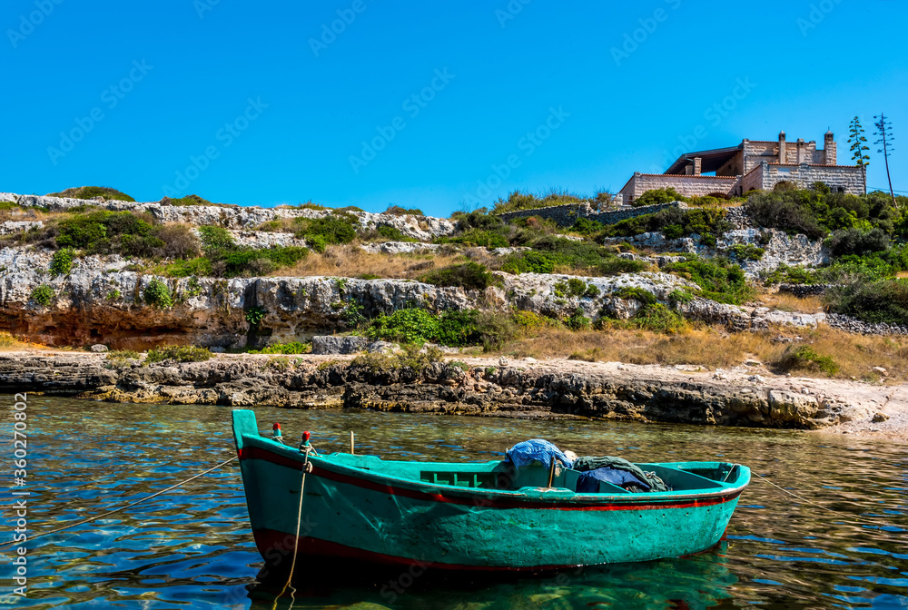 A green fishing boat moored in an inlet near Polignano a Mare, Puglia, Italy