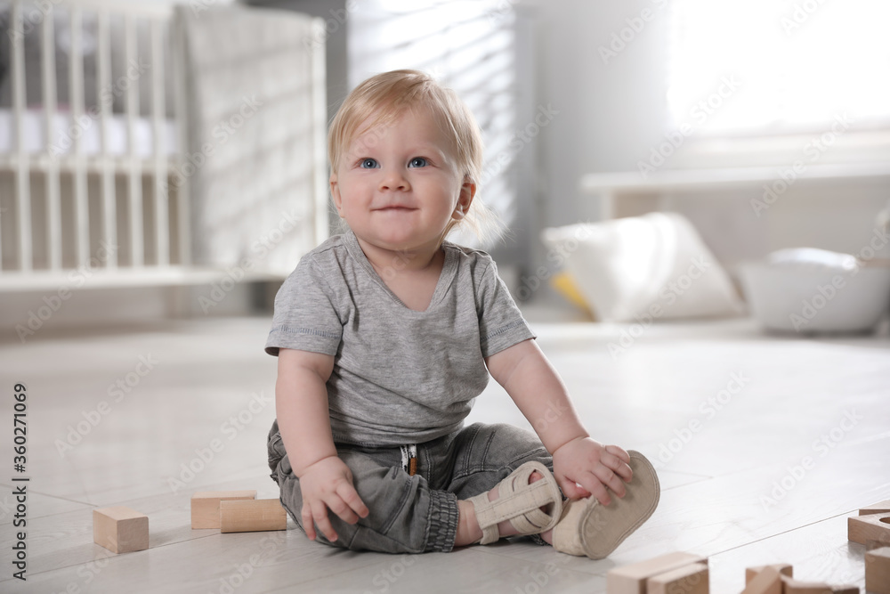 Adorable little baby with wooden blocks on floor at home Adorable little baby with wooden blocks on floor at home