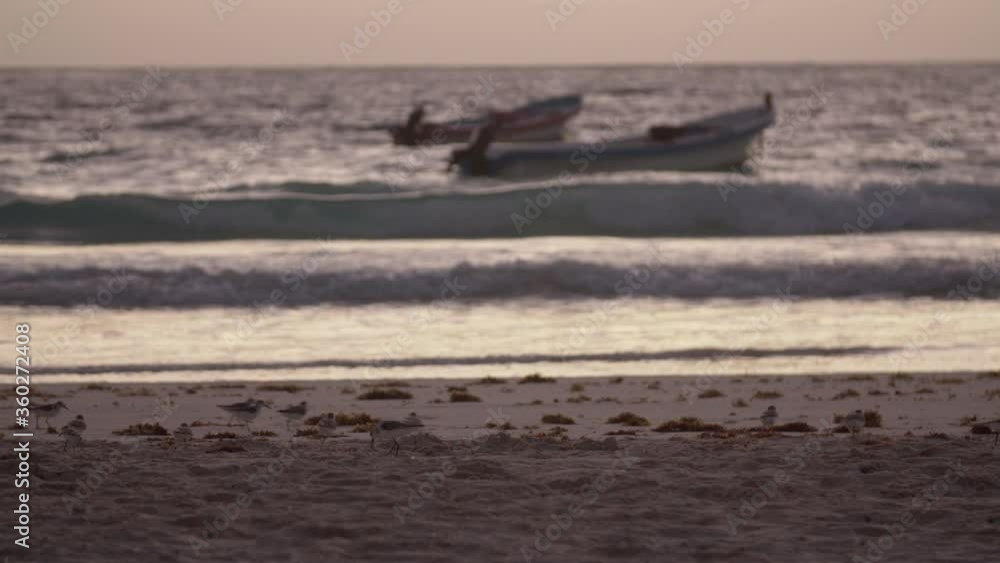 A sunrise with some boats floating over the waves in the coast of Tulum, Mexico. A sunrise with some boats floating over the waves in the coast of Tulum, Mexico.