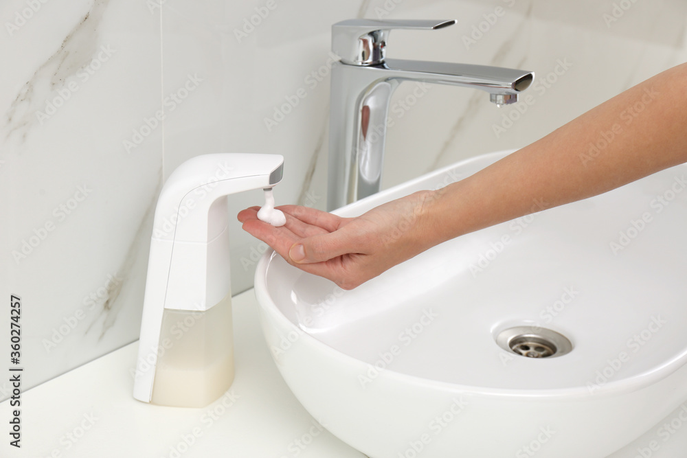 Fototapeta premium Woman using automatic soap dispenser in bathroom, closeup