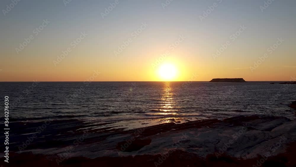 Drone shot starting on a horseback rider standing on shore then pushing in on the sun as it sets over the sea. Drone shot starting on a horseback rider standing on shore then pushing in on the sun as it sets over the sea.