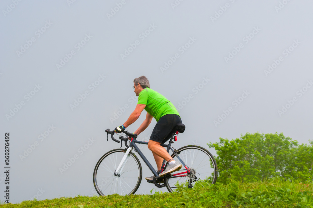 Riding adult cyclist on his road bicycle in a park Riding adult cyclist on his road bicycle in a park