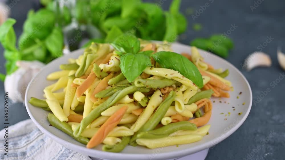 Homemade apulian pasta of different colors cooked with basil, garlic, olive oil. Typical dish of Southern Italy of Puglia, Salento. Orecchiette and Maccheroni. 4k video.