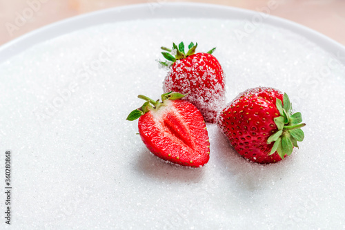 The berries of a ripe tasty strawberry lie on sugar. Summer berries. Background with strawberries. Free space in the photo.