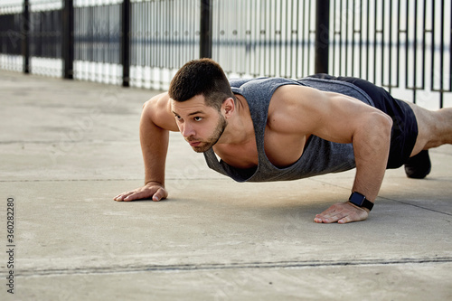 Young male athlete practicing push-ups on footpath