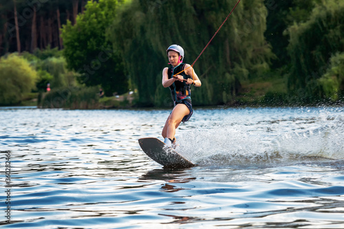 Woman riding wakeboard. Cuts waves and raises splash in a summer lake photo