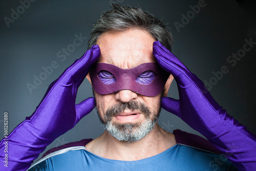 Close-up of superhero with headache against gray background photo