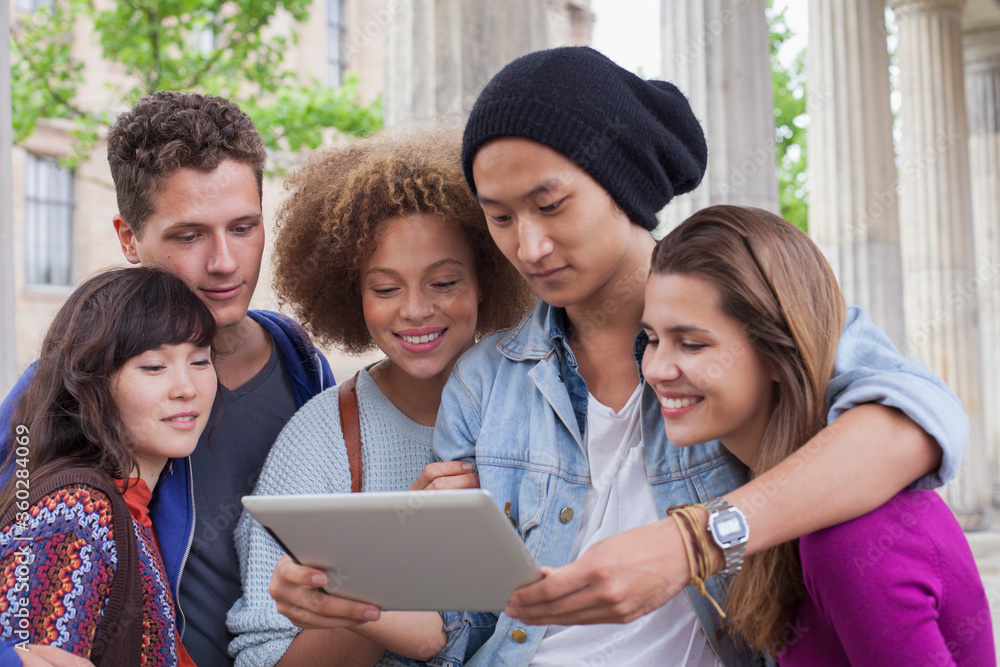 Young man showing digital tablet to multi-ethnic friends Young man showing digital tablet to multi-ethnic friends