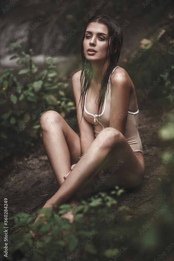 Thoughtful sensuous young woman in swimwear sitting at forest Thoughtful sensuous young woman in swimwear sitting at forest