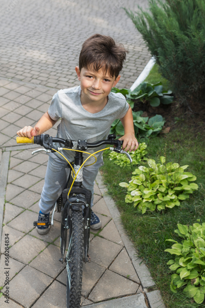 High angle portrait of boy riding bicycle on street by plants High angle portrait of boy riding bicycle on street by plants
