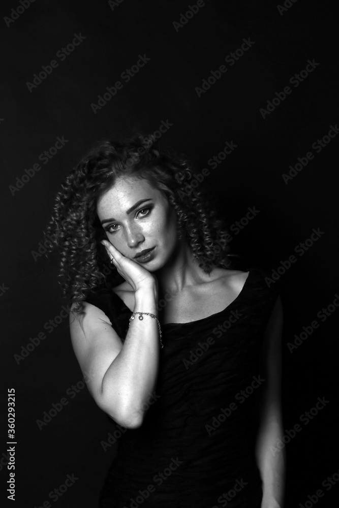 Fototapeta premium Black and white portrait of a cute curly girl in a black dress
