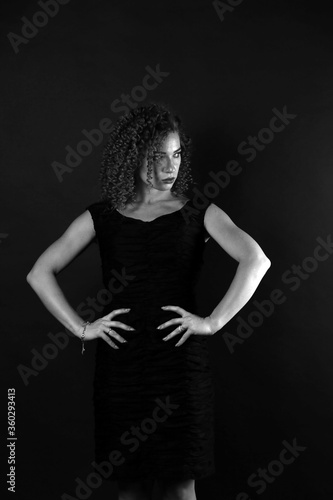 Black and white portrait of a cute curly girl in a black dress