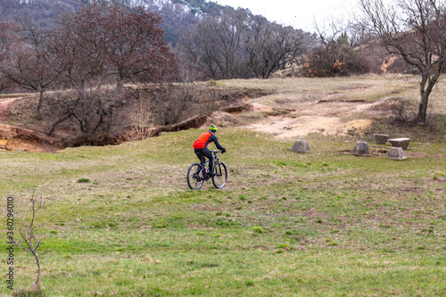 Young cyclist in red riding bike on grassy hill. Active lifestyle, extreme sport concept