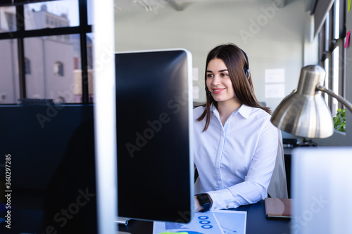 Caucasian woman working on computer with headphone set 