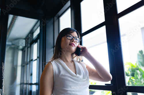 Asian woman having a phone call and looking outside